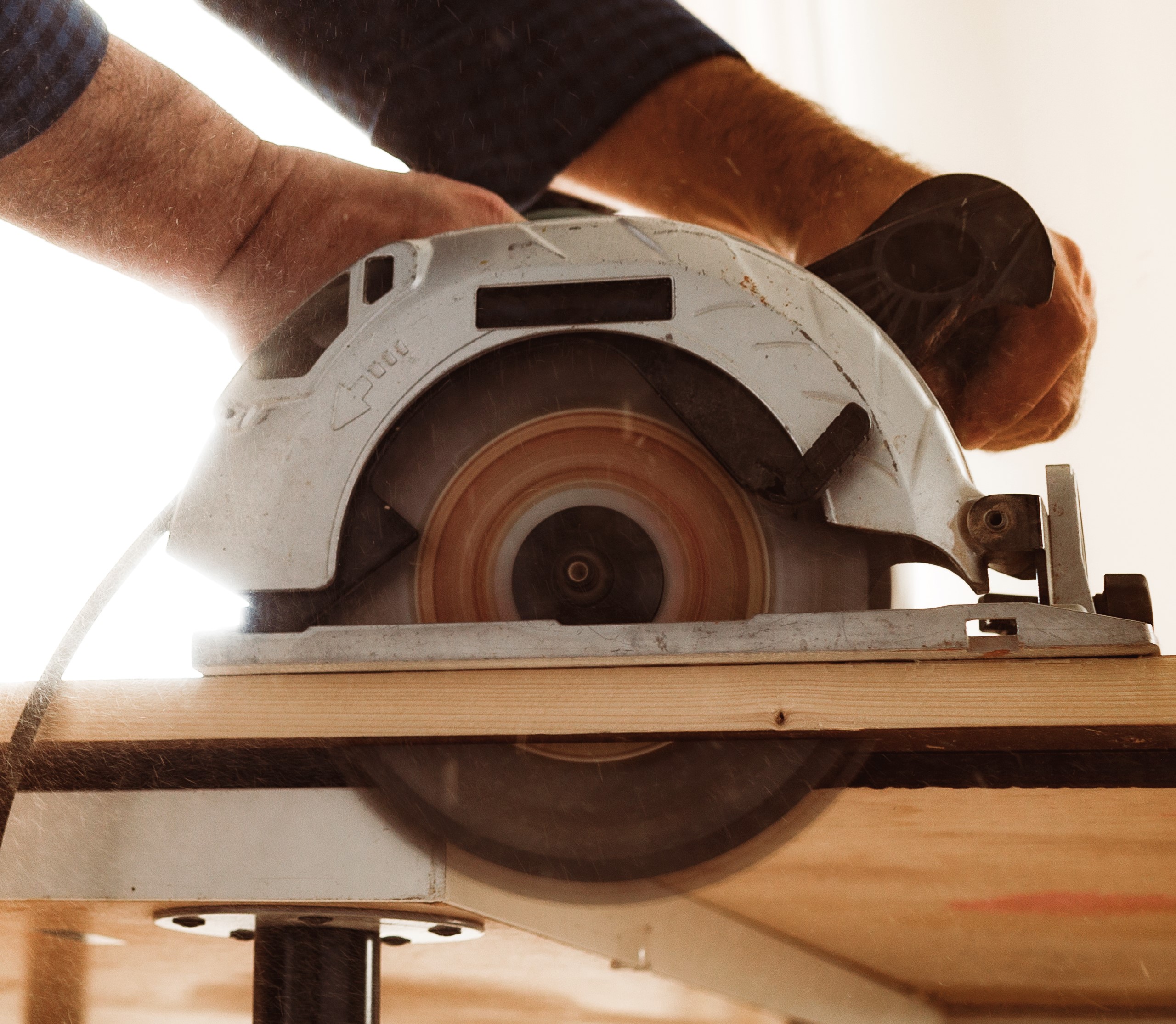 carpenter-hands-cutting-wood-with-electrical-saw